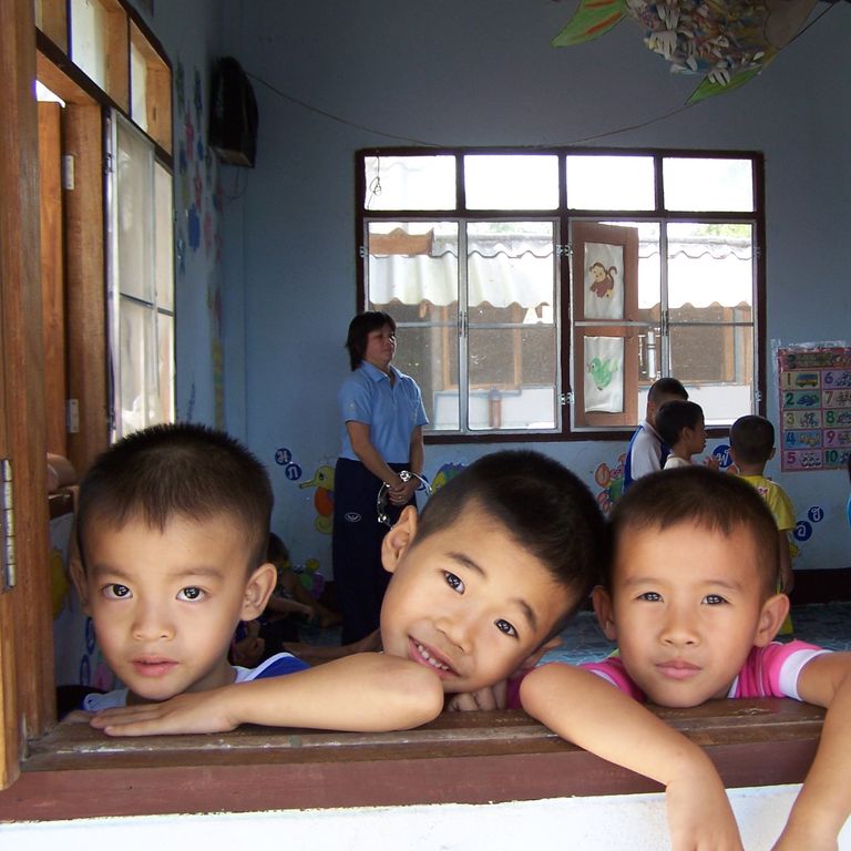 photo of 3 schoolboys looking out of a classroom window