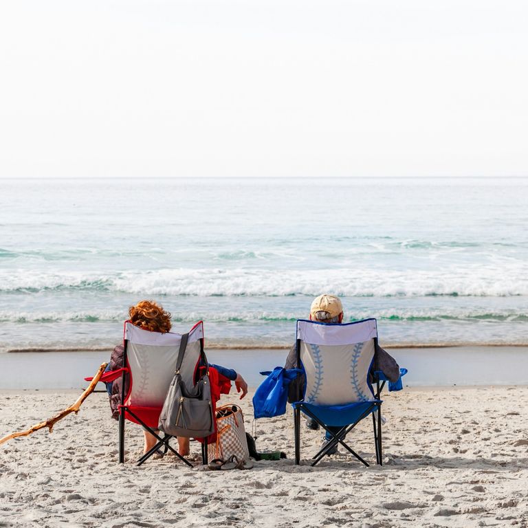 photo of 2 older people sitting on a beach