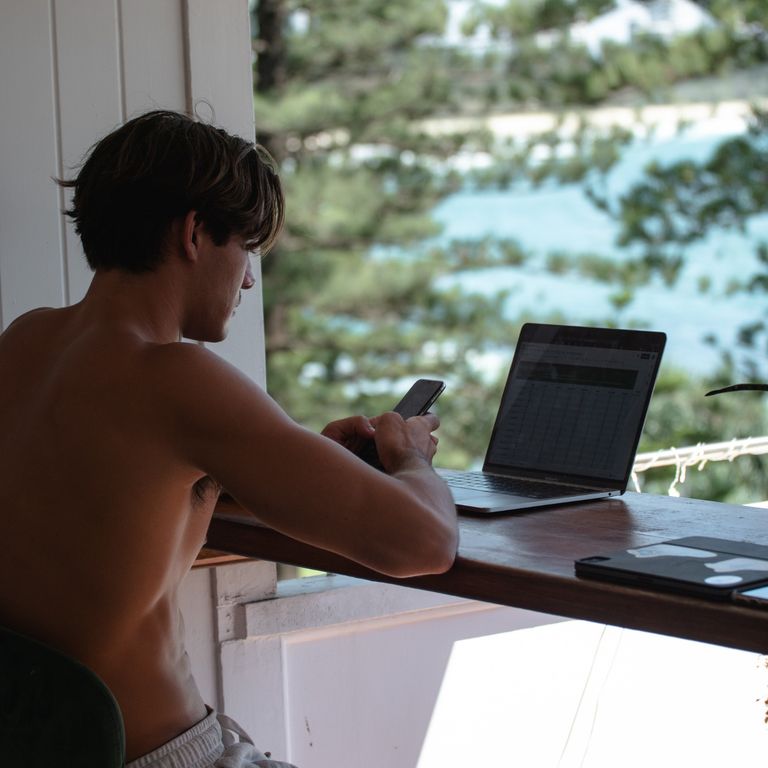 photo of shirtless man at desk on a laptop
