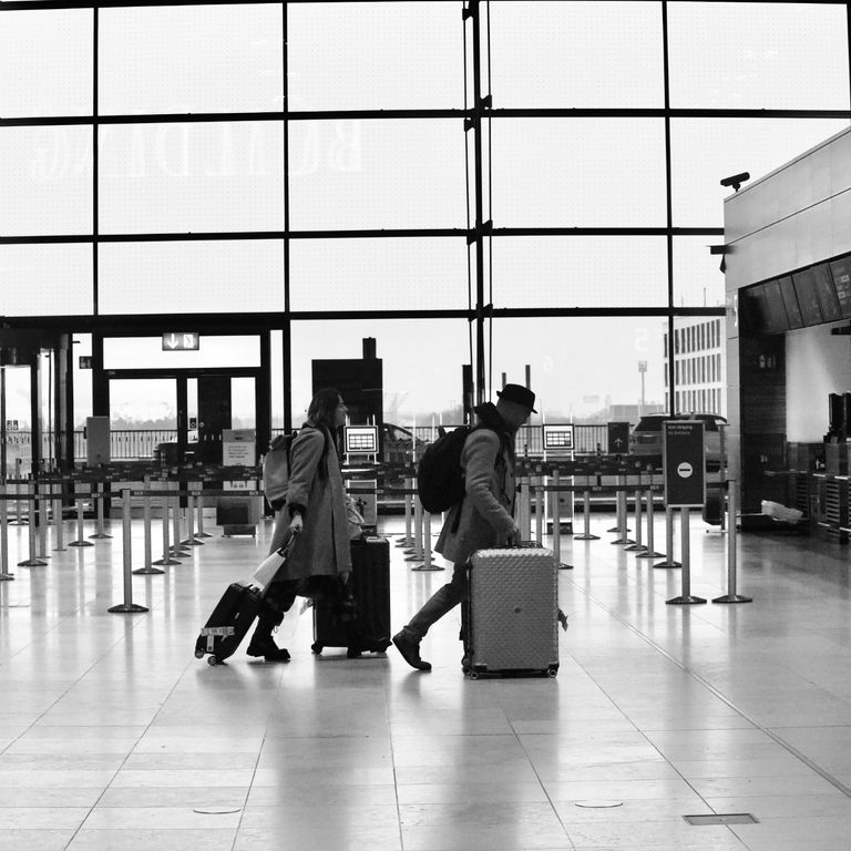 image of passengers dragging luggage across an airport departure hall